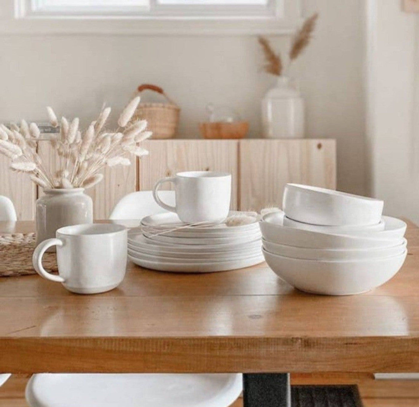Fable dinnerware on table. Speckled white bowls, plates, and mugs.