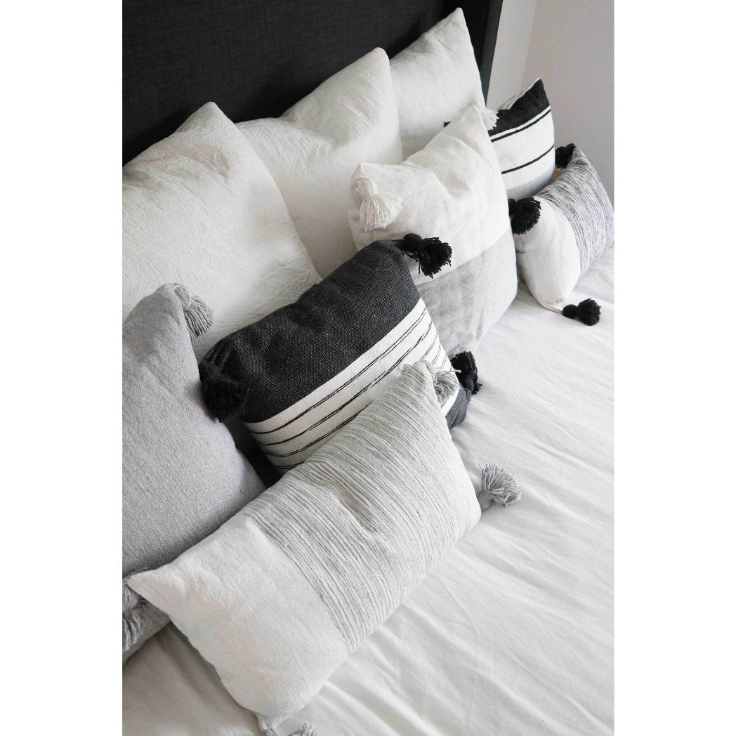 Half Light Grey Pom Pom Pillows on bed.