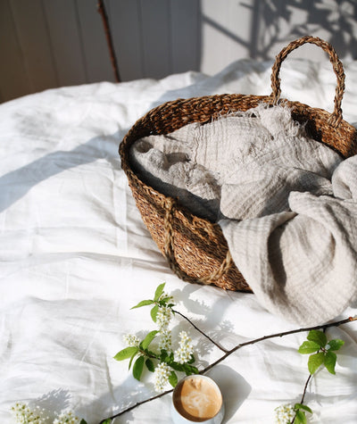 Hampton Almond Throw: In basket on bed. Colour: Almond, Material: 100% linen, Origin: Made in Portugal
