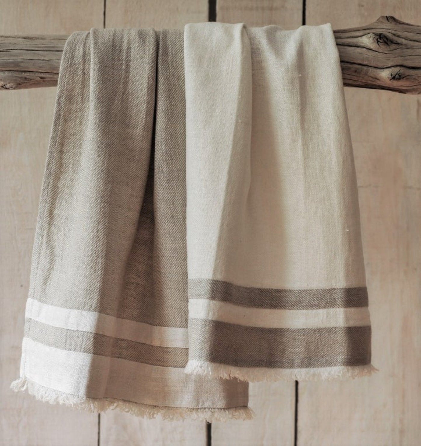 Lipari Linen Towels hung on driftwood. Beige and white towels.
