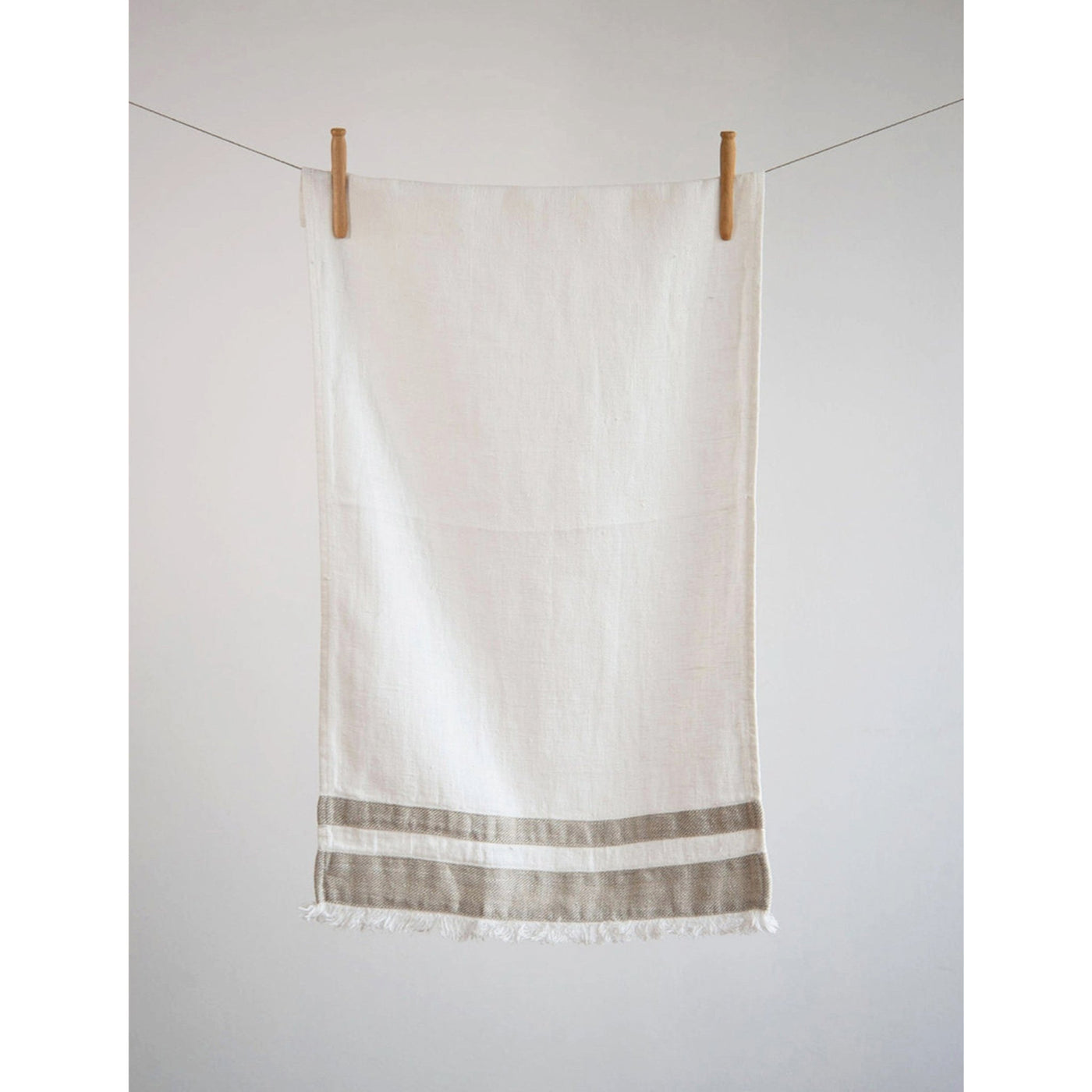 Lipari Linen Towel in White with beige stripes and fringed edges. Hanging.