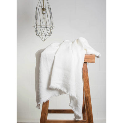 Lipari Linen Throw with Fringes, Rustic White: on wooden stool.