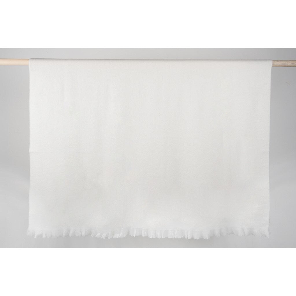 coconut white alpaca throw Super-Soft with fringed edges hung over wooden rod