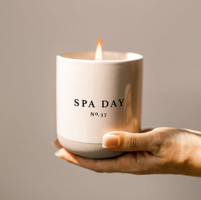 Sweet Water Decor Candles: Spa Day Soy candle held in the palm of a hand.  Cream stoneware with matte beige bottom.