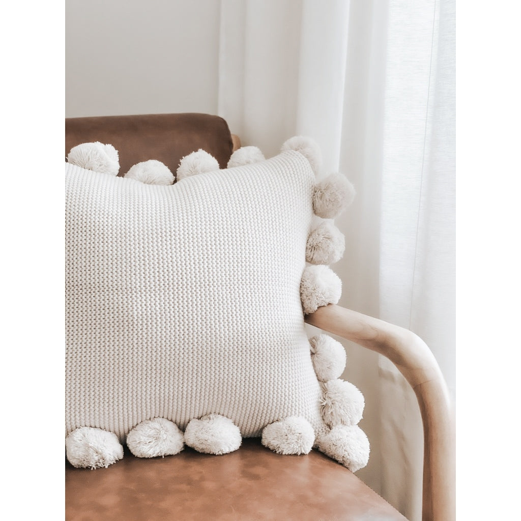 Square Knit Poms Pillow on leather chair