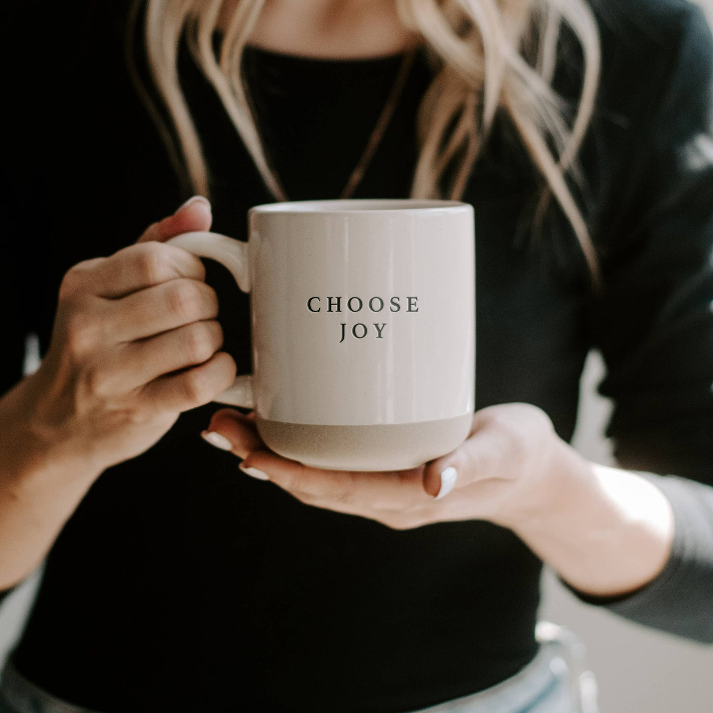 Stoneware coffee Mug held in hands with Choose Joy words on both sides.